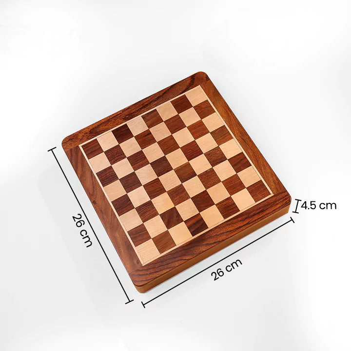 Wooden chessboard on a beige surface with books and a pen in the background