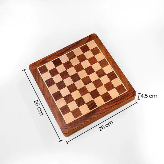 Wooden chessboard on a beige surface with books and a pen in the background