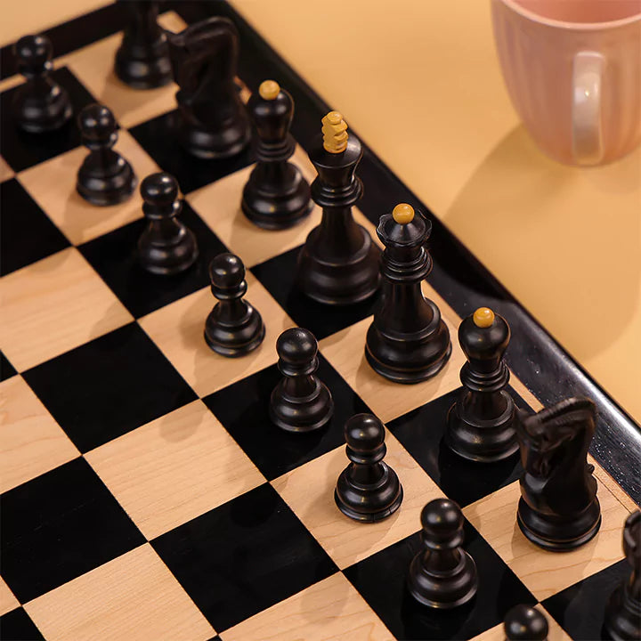 Close-up of a chessboard with black and white pieces on a wooden surface.