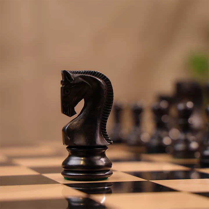 Black chess piece on a chessboard with a blurred background