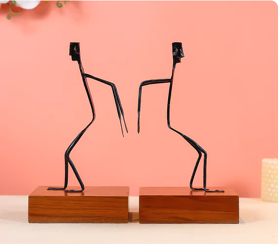 Two black wire sculptures on wooden bases against a pink background